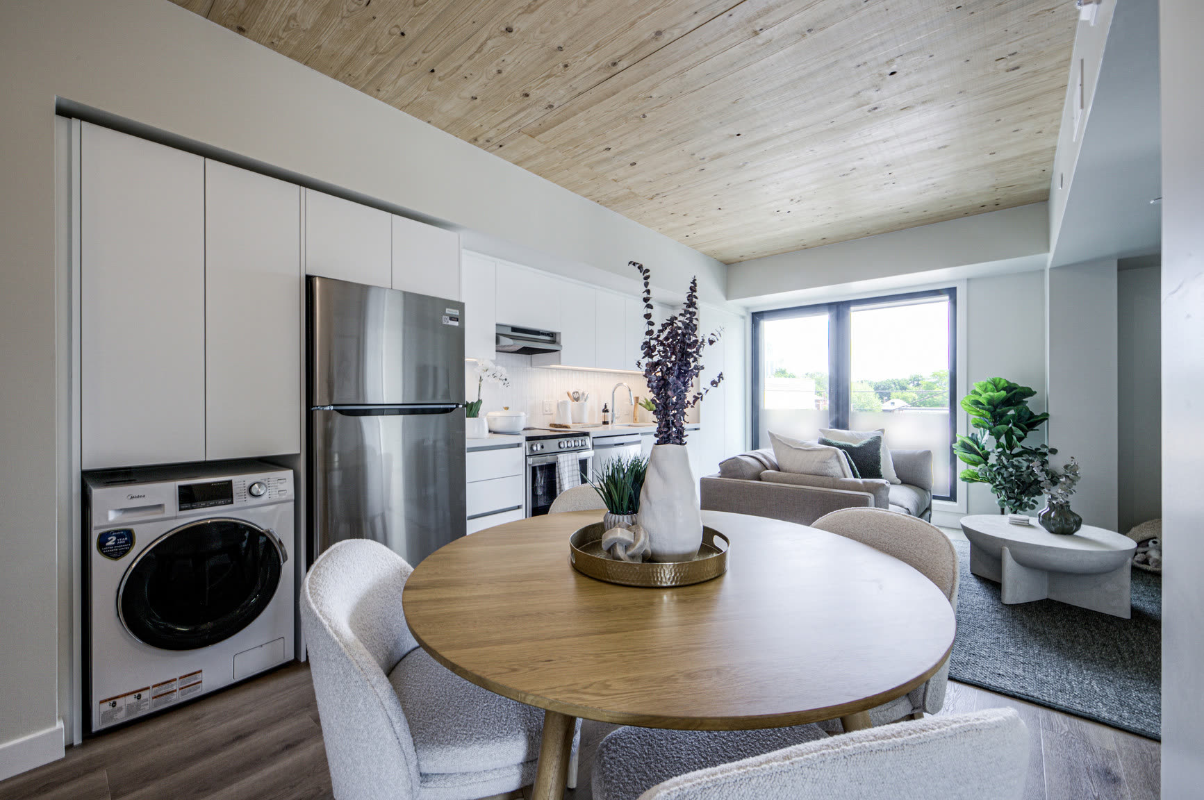 Dining table beside a kitchen with stainless appliances and in-suite laundry